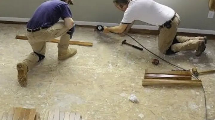 Two workers installing replacement flooring after water damage