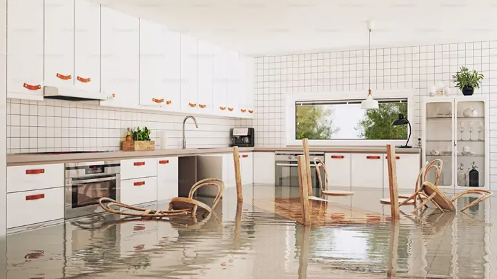 Kitchen with water on the floor and chairs standing in it